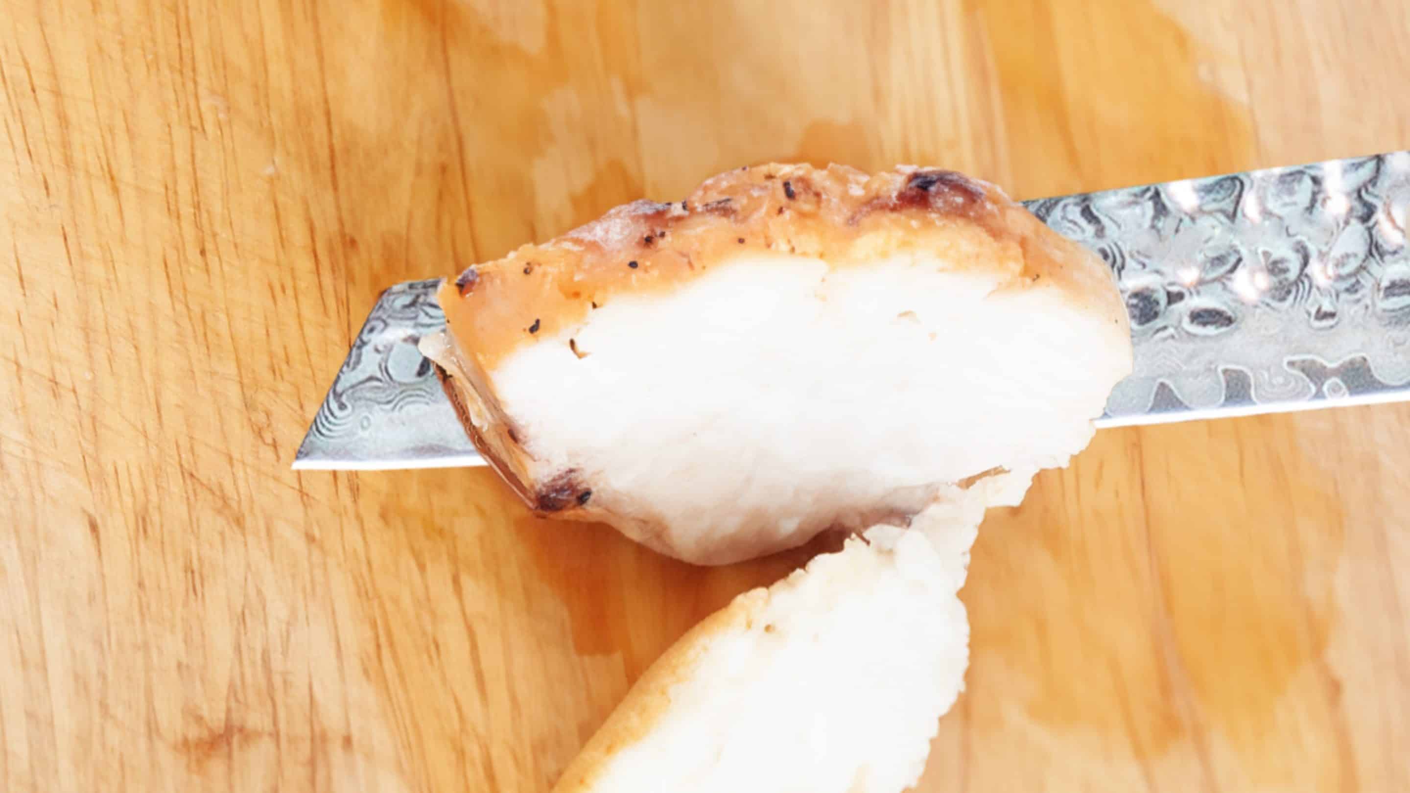 Baked chicken breast on a knife.